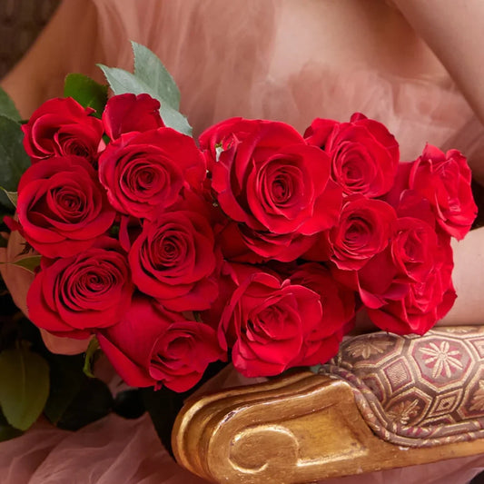 Buquê de rosas vermelhas elegantes com modelo em cadeira dourada de design