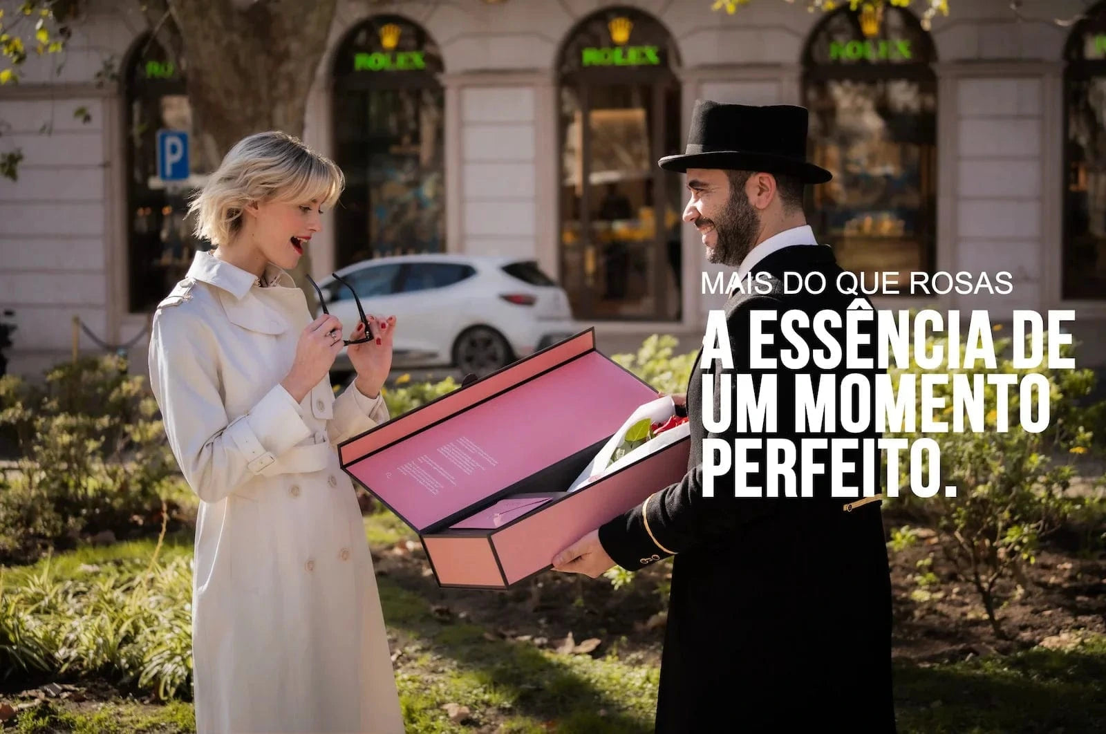 Entrega de rosas de luxo em Lisboa – homem elegante oferece caixa rosa a mulher sorridente num momento especial ao ar livre
